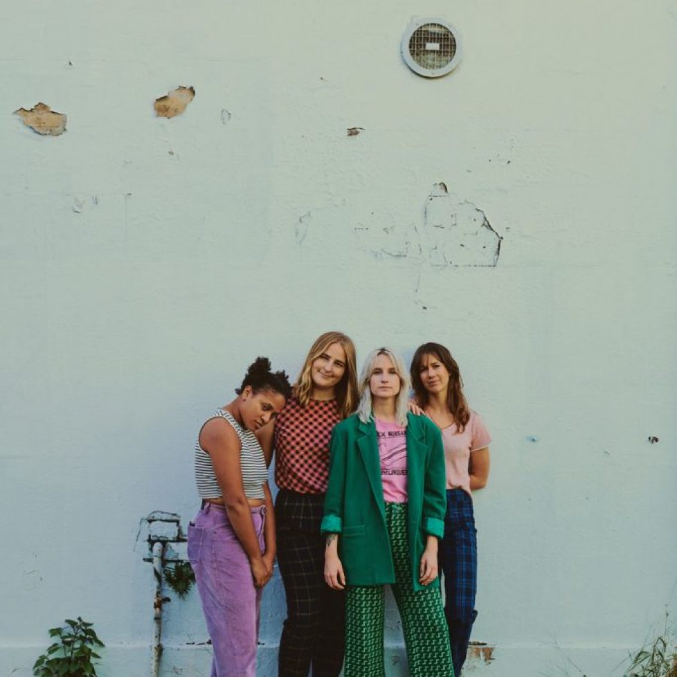 The Buoys band in front of light blue wall